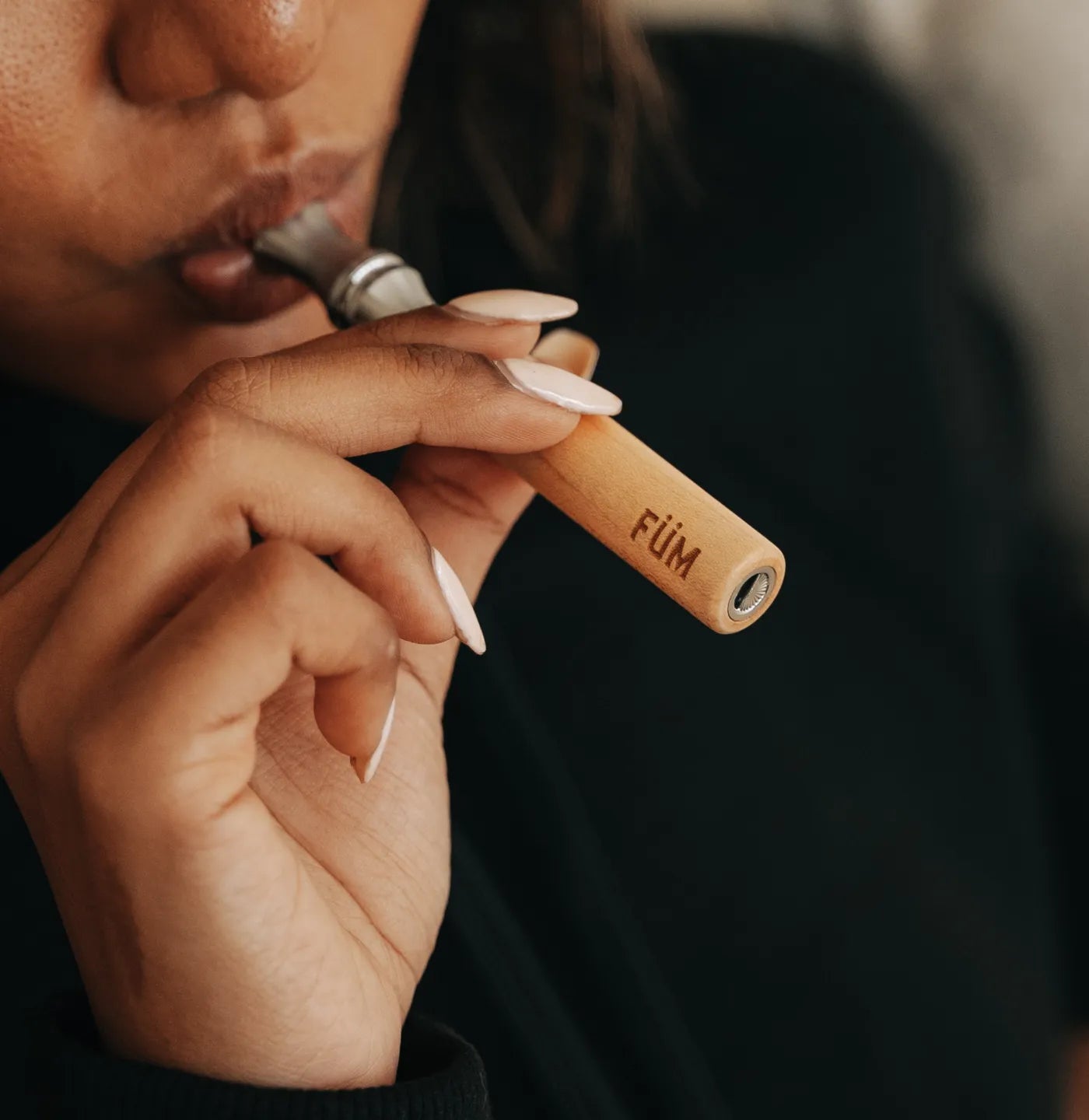 Person holding a wooden vape pen with 'FUM' branding.